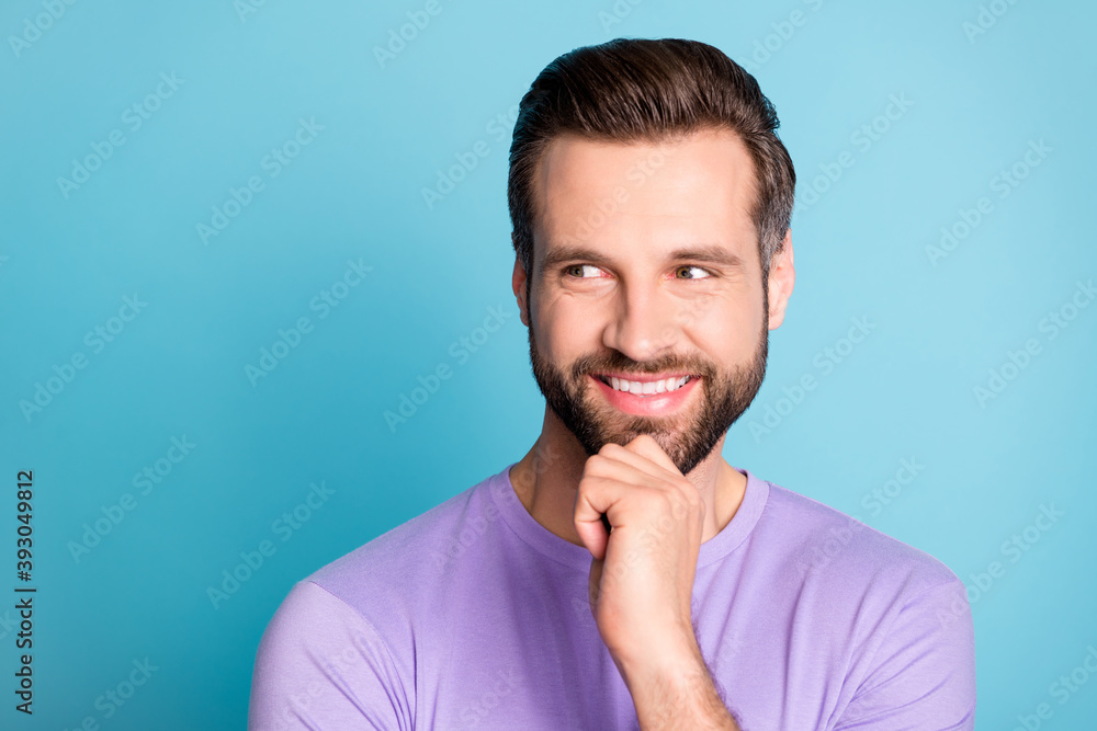 Photo of young cheerful young man happy positive smile hand touch chin think look empty space isolated over blue color background
