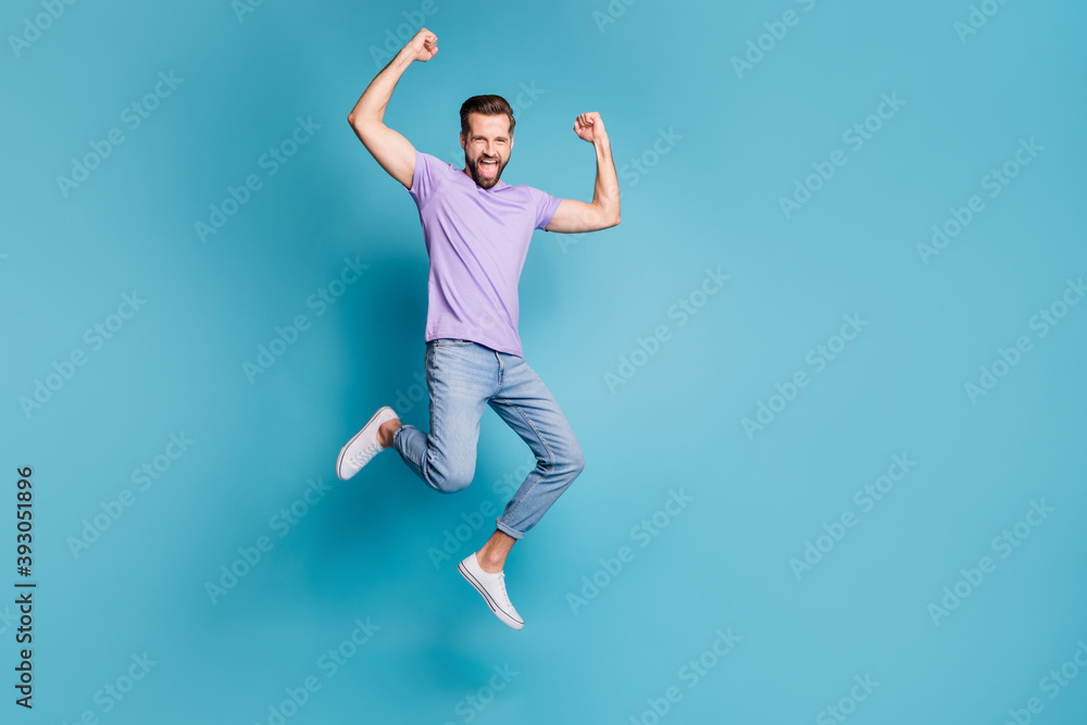 Full length body size photo of jumping high cheerful bearded man gesturing like winner yelling isolated on bright blue color background