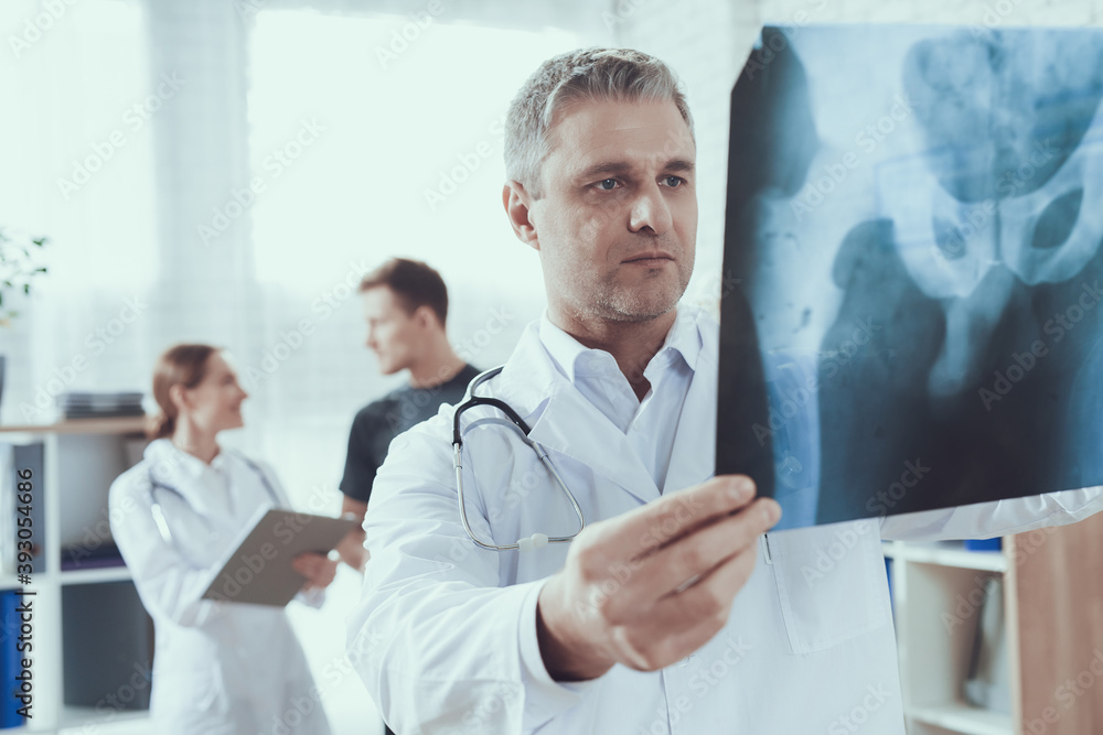 A male doctor stands in an x ray and has bad news. A male doctor stands in an x ray and has bad news.