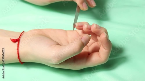 The hands of a girl who files her nails with a nail file. Close up.