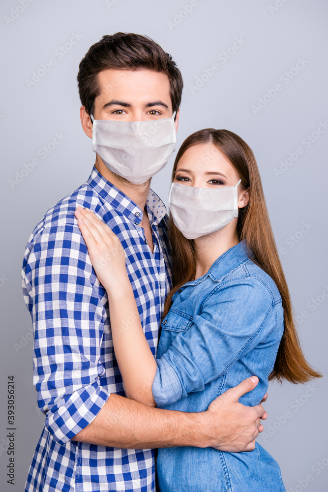 Vertical photo portrait of two young cute lovers hugging wearing white face masks isolated on white colored background