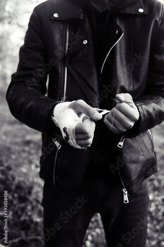 The fighter is bandaging his hands. The concept of preparation for a fight, sports competition, boxing and kickboxing. A man in a leather jacket.