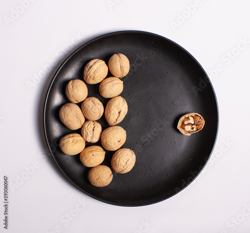 Walnuts. On a black plate. White background.