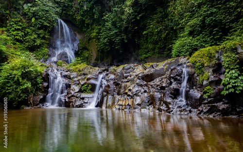 Waterfall landscape. Beautiful hidden Pengibul waterfall in rainforest. Tropical scenery. Water reflection. Slow shutter speed  motion photography. Nature background. Bali  Indonesia