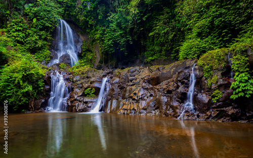 Waterfall landscape. Beautiful hidden Pengibul waterfall in rainforest. Tropical scenery. Water reflection. Slow shutter speed  motion photography. Nature background. Bali  Indonesia