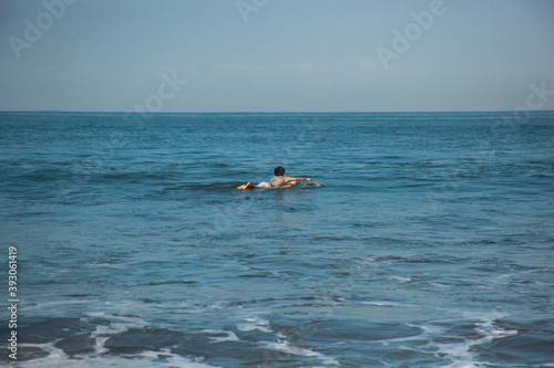 A surfer swim on surfing board in west coast Pangandaran