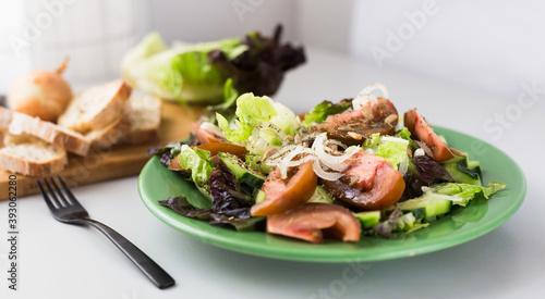 vegetable salad of greens, tomatoes and cucumbers on a green plate