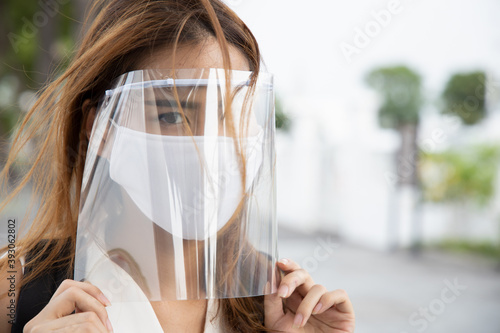woman wearing face mask and face shield, observing new normal social distancing measure to flatten the curve and prevent virus infection by taking extra physical distance precaution photo