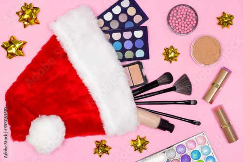 Makeup products with Santa hat and gift bows. Top view, flat lay. Make-up cosmetics as Christmas and New Year present concept © JAYANNPO