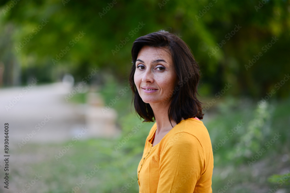 portrait of beautiful and cheerful mature woman outdoor in a park during a sunny summer day