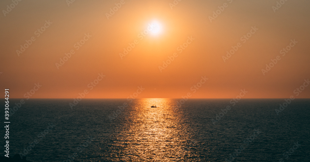 Dramatic sea sunset with the only fishing boat. Loneliness at the sea. Isolated fisherman in the sunset. Isolation and loneliness concept.