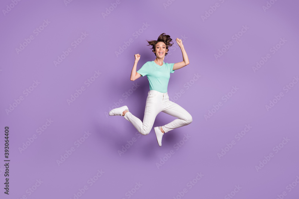 Full size profile photo of nice optimistic girl jumping wear white sneakers pants blue t-shirt isolated on violet color background