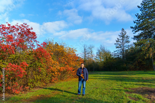 portrait of a man posing in autumn park, bright colorful leaves as background