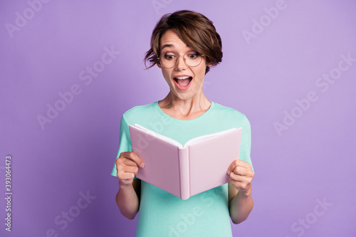 Photo of sweet impressed short brown hairdo lady read planner wear spectacles blue t-shirt isolated on violet background