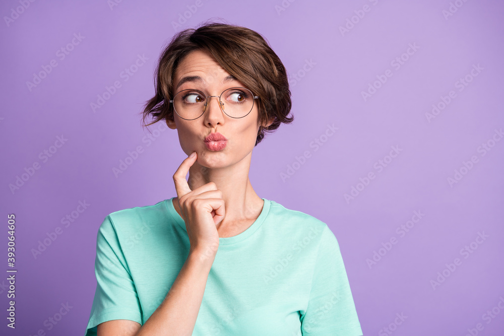 Photo of interested pretty short brown hairdo girl hand chin look empty space wear spectacles blue t-shirt isolated on violet background