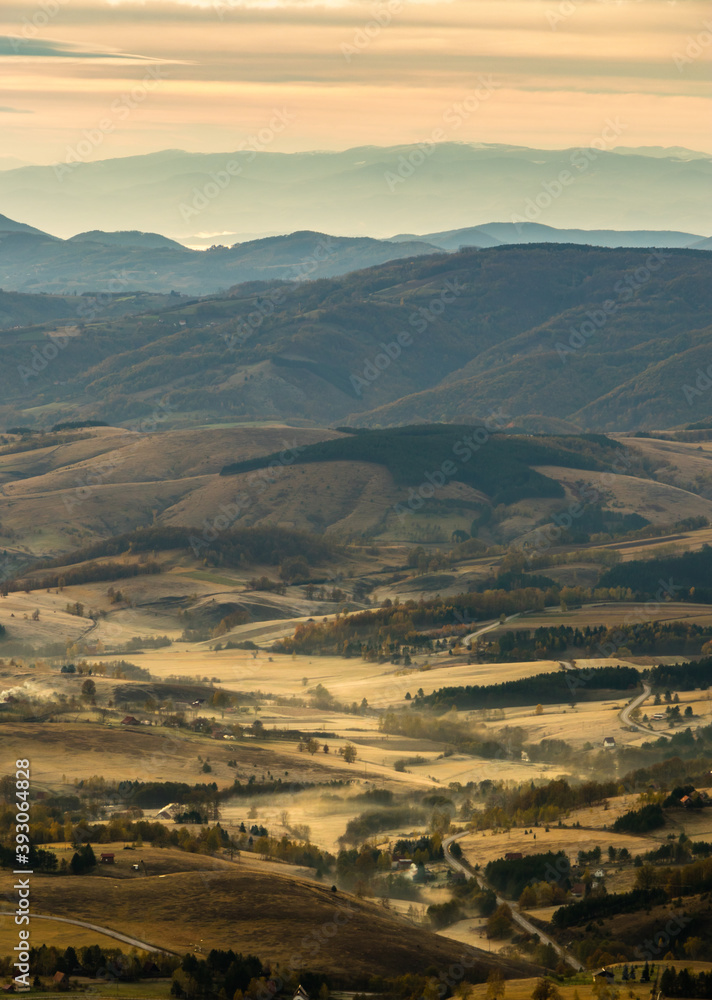 Early morning foggy sunrise with dramatic lighting over Serbian countryside. Hills with curvy roads and houses. Break with an amazing view. Early morning foggy sunrise with dramatic lighting over Serbian countryside. Hills with curvy roads and houses. Break with an amazing view.