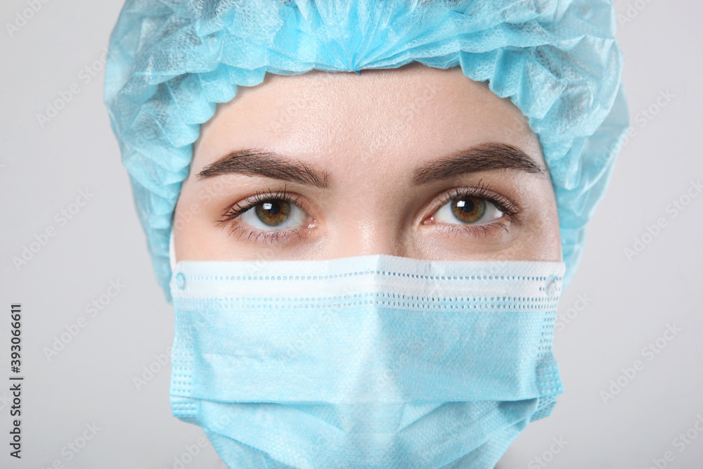 Young woman doctor in a protective mask on a light background Young woman doctor in a protective mask on a light background