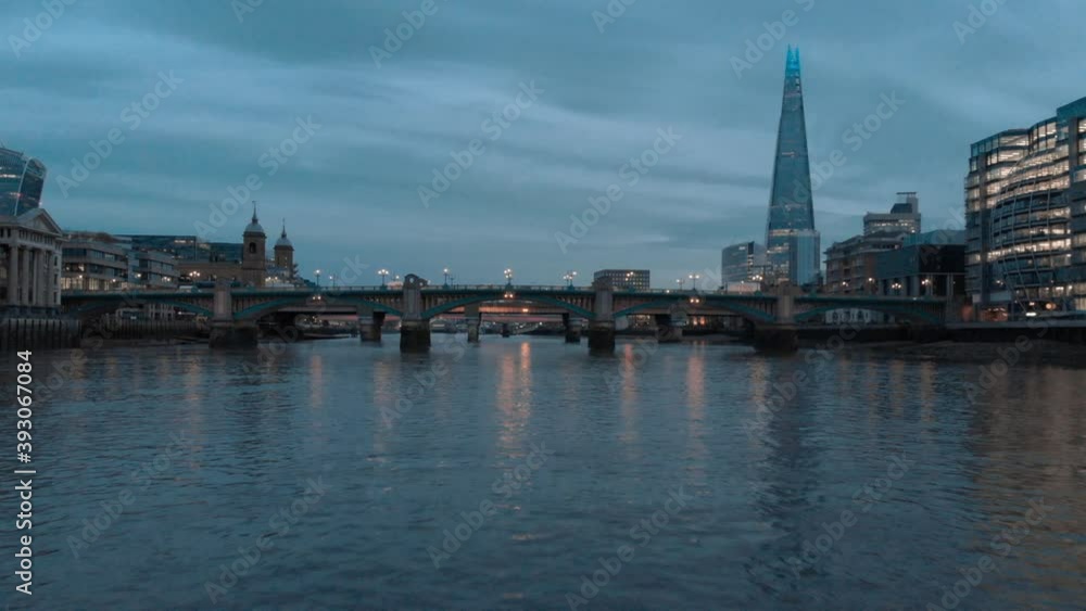 Low drone shot along thames river under southwark bridge shard in background at sunset blue hour Low drone shot along thames river under southwark bridge shard in background at sunset blue hour