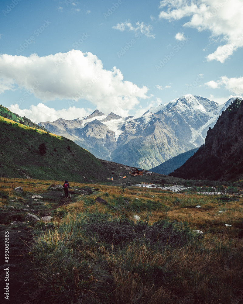 a girl walks along a path with a backdrop of picturesque mountains