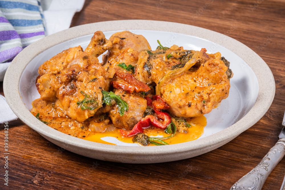 Ready Italian dish - Tuscan chicken with sun-dried tomatoes, tomato paste, spinach, cream and cheese on a plate on a wooden table Ready Italian dish - Tuscan chicken with sun-dried tomatoes, tomato paste, spinach, cream and cheese on a plate on a wooden table