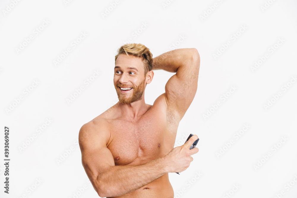 Happy caucasian shirtless man smiling while using deodorant