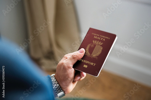Business Man in a suit is holding malta passport in left hand