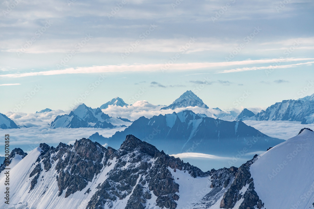Beautiful panorama of high rocky mountains with mighty glaciers and snowy peaks against the blue sky and clouds