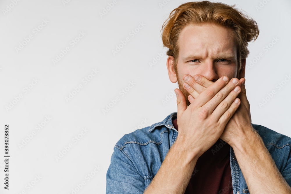 Serious handsome ginger guy looking at camera and covering his mouth Serious handsome ginger guy looking at camera and covering his mouth