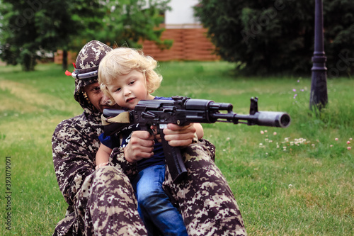 Father and son in camouflage ready to play in laser tag shooting game outside. Concept of father's day, military war game, father's return home.