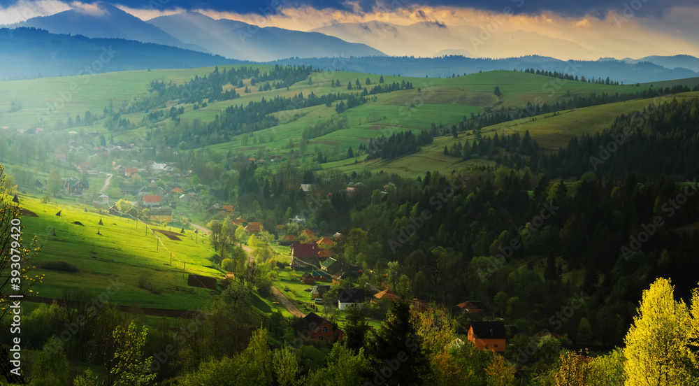 Spring morning rural landscape in the Carpathian mountains. Dramatic sky before dawn, a ray of light breaks through the clouds.