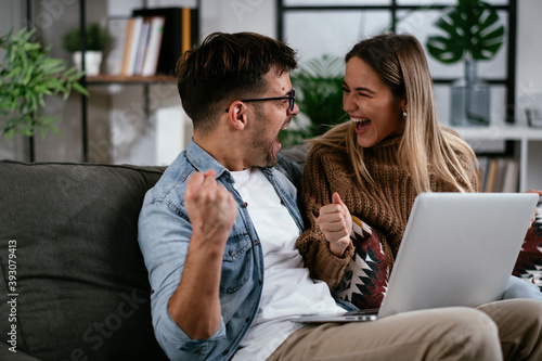 Happy young couple with laptop at home photo