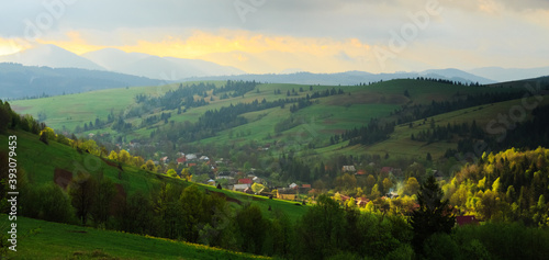 Spring morning rural landscape in the Carpathian mountains. Dramatic sky before dawn, ray of sun trying to break through the clouds.