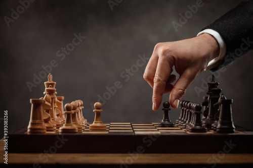 Chess pieces on the board. Chess player makes a move the black pawn forward. Game of chess. Selective focus. Strategy, management or leadership concept. 