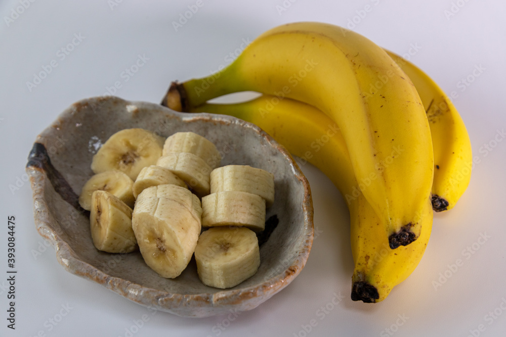 Sliced banana on plate and a bunch of bananas on white background. Sliced banana on plate and a bunch of bananas on white background.