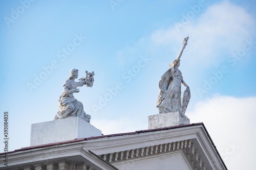 White statues on the roof of a house against a clear sky