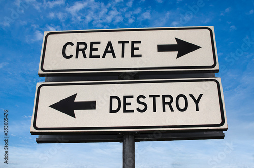 Create versus destroy. White two street signs with arrow on metal pole with words. Directional road. Crossroads Road Sign, Two Arrows on blue sky background. Two way road sign with text.