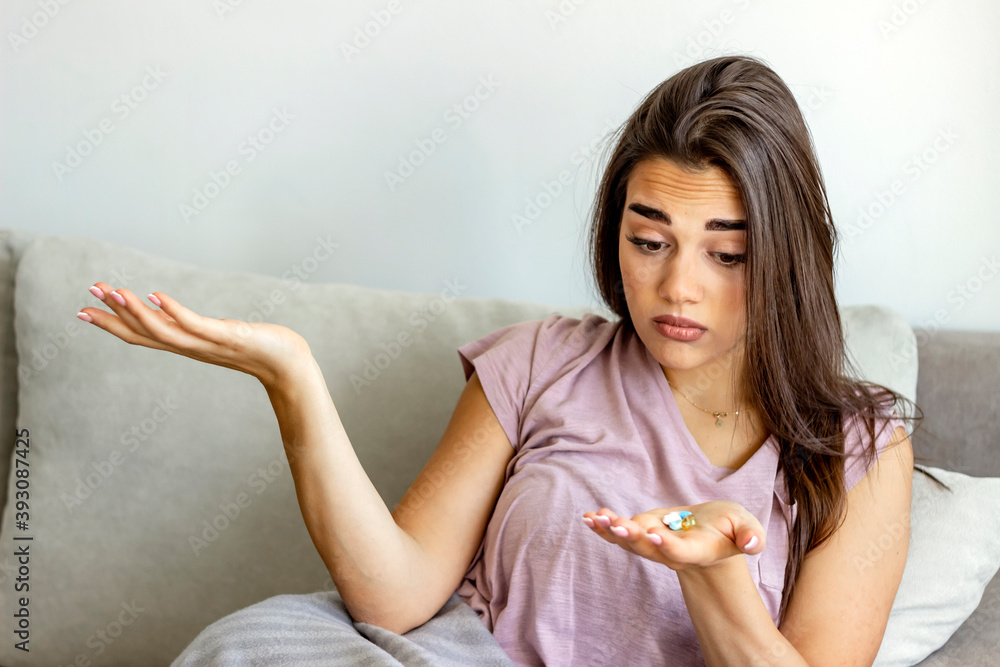 Photo of a woman holding bunch of pills in hand,looking at them,taking painkiller to relieve painful feelings migraine headache,antidepressant or antibiotic medication.Medicine and healthcare concept. Photo of a woman holding bunch of pills in hand,looking at them,taking painkiller to relieve painful feelings migraine headache,antidepressant or antibiotic medication.Medicine and healthcare concept.