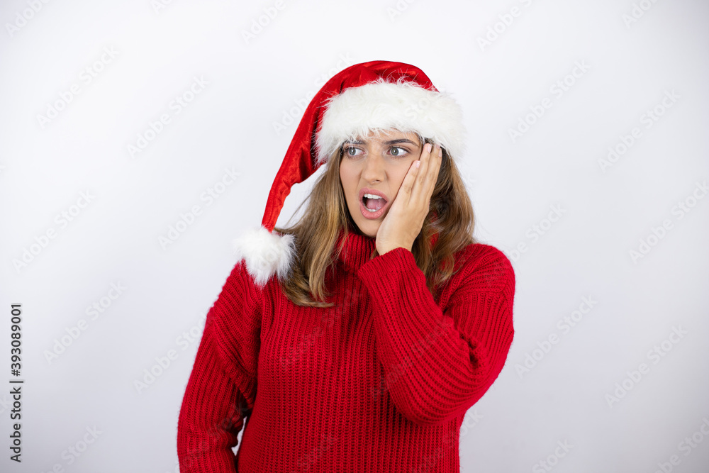 Young pretty blonde woman wearing a red casual sweater and a christmas hat over white background touching mouth with hand with painful expression because of toothache or dental illness on teeth Young pretty blonde woman wearing a red casual sweater and a christmas hat over white background touching mouth with hand with painful expression because of toothache or dental illness on teeth