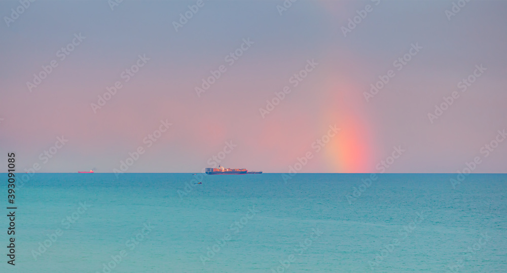 Container cargo ship with stormy sea and sky, amazing rainbow in the background Container cargo ship with stormy sea and sky, amazing rainbow in the background