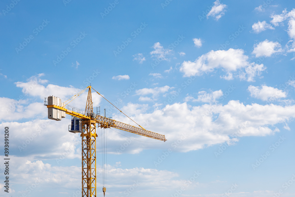 Yellow tall construction crane against the background of blue sky and clouds. Copy space, template for text Yellow tall construction crane against the background of blue sky and clouds. Copy space, template for text