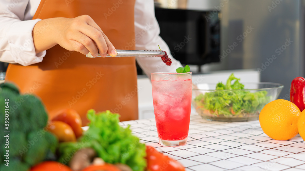 Women hands prepairing mocktail by putting sweet mulberry into a glass with an iced pink color drink. Women hands prepairing mocktail by putting sweet mulberry into a glass with an iced pink color drink.