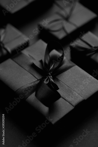 Black Christmas concept. Close up on elegant black matte wrapped gifts with ribbon.