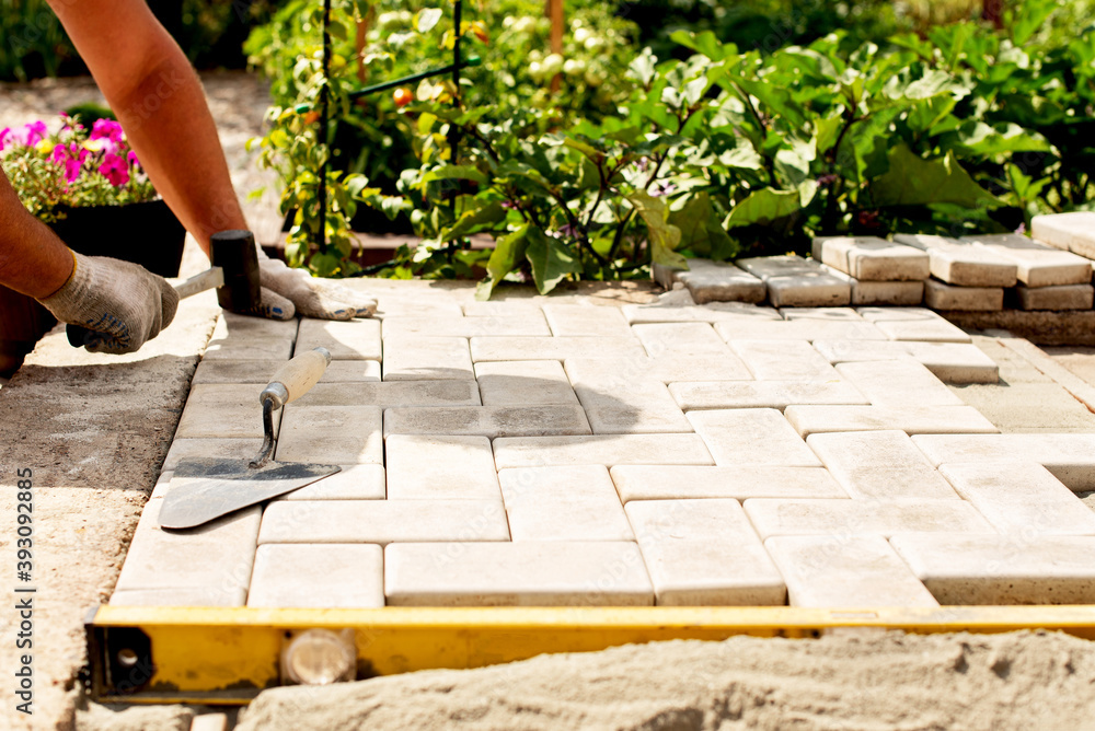 The master lays paving stones in layers. Garden brick pathway paving ...