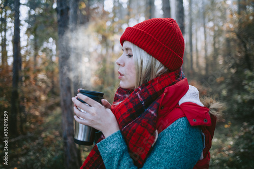 Woman backpacker drinking steaming coffee in a forest © Suteren Studio