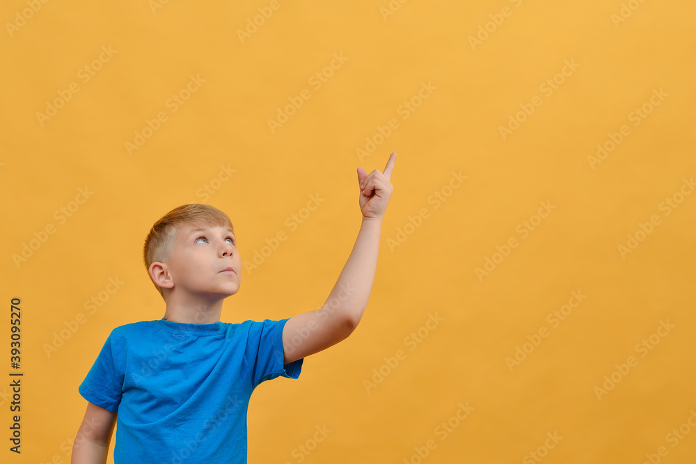 Surprised boy on a yellow background shows thumbs up and looks to the side. Surprised boy on a yellow background shows thumbs up and looks to the side.