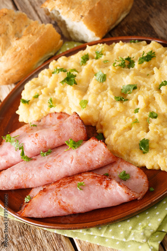 pease pudding is made from cooking yellow split peas served with fried ham closeup in the plate on the table. vertical