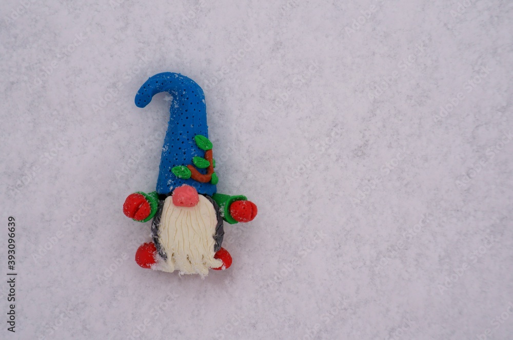 Figure of a gnome made of plasticine on the background of snow. Figure of a gnome made of plasticine on the background of snow.