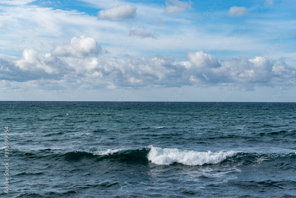 白波が打ち付ける青空の海岸と地平線