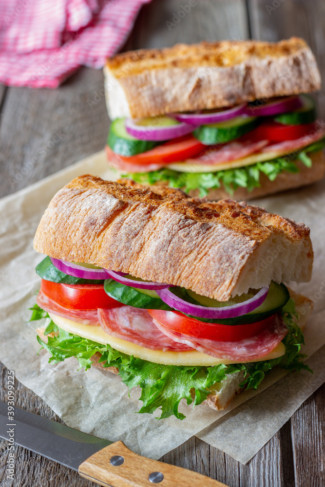 Sandwich with sausage, cheese, green salad, tomatoes, cucumbers and onions. Fast food. Breakfast. Healthy eating. Sandwich with sausage, cheese, green salad, tomatoes, cucumbers and onions. Fast food. Breakfast. Healthy eating.