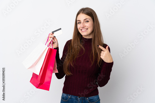 Young woman over isolated white background holding shopping bags and a credit card